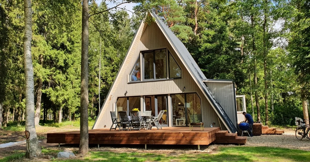 Avrame A-frame domy: Stavebnice ve tvaru áčka, kterou postaví tři lidé 2 Dřevěný A-frame dům v zeleném lese s terasou a venkovním posezením