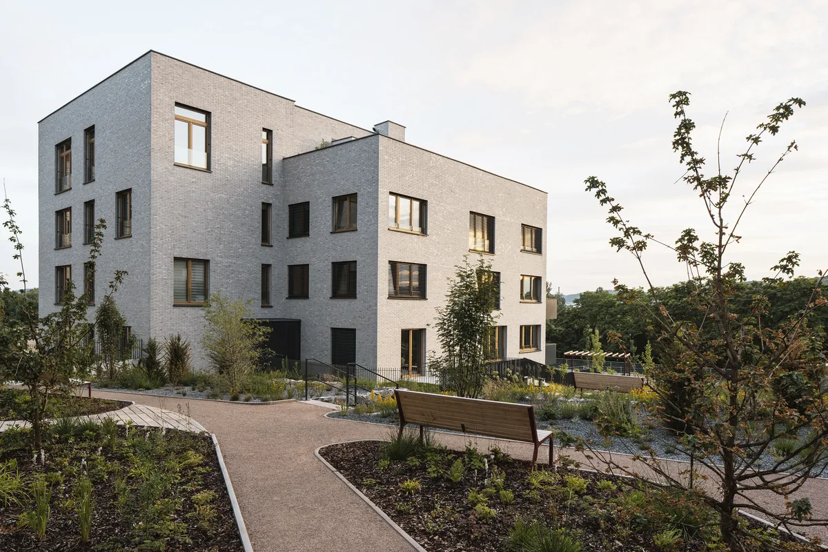 Bytový dům C v Modřanském cukrovaru: štítek A, lofty a recyklace šedé vody 3 Fasáda z režného cihelného obkladu a parkové úpravy s lavičkami u bytového domu