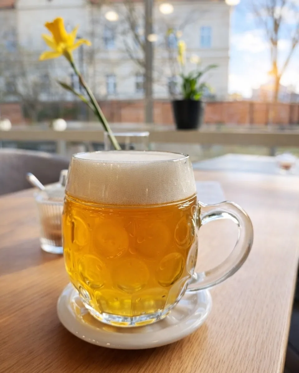 Earnest v Kroměříži: kavárna, restaurace a bowling v Domě kultury 3 Krýgl světlého piva s pěnou na dřevěném stole u prosklené stěny kavárny