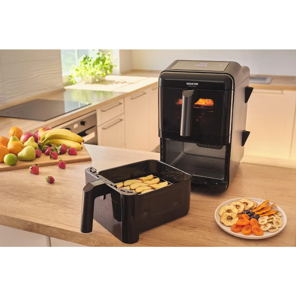 Fritéza Sencor DUAL STACK má dva koše nad sebou s objemem 11,6 l a připraví až 4 jídla 2 Fritéza Sencor DUAL STACK na kuchyňské lince, před ní vysunutý koš se sušenými plátky ovoce