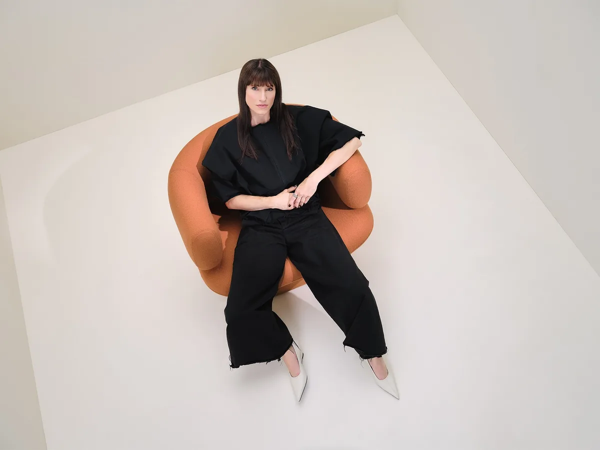 Z jednoho křesla celá kolekce: Lucie Koldová navrhla pro LD Seating sezení Dafna 1 Žena v černém sedí v terakotovém lounge křesle Dafna na světlém pozadí